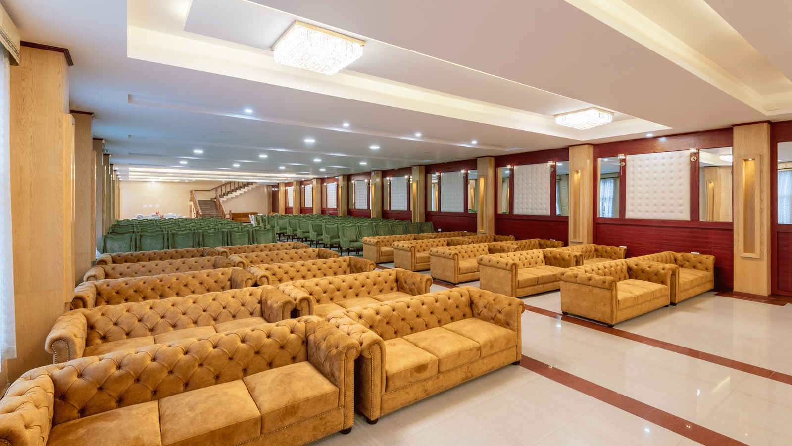 A spacious DLS Hotels banquet hall featuring rows of tufted sofas and polished flooring for large events.