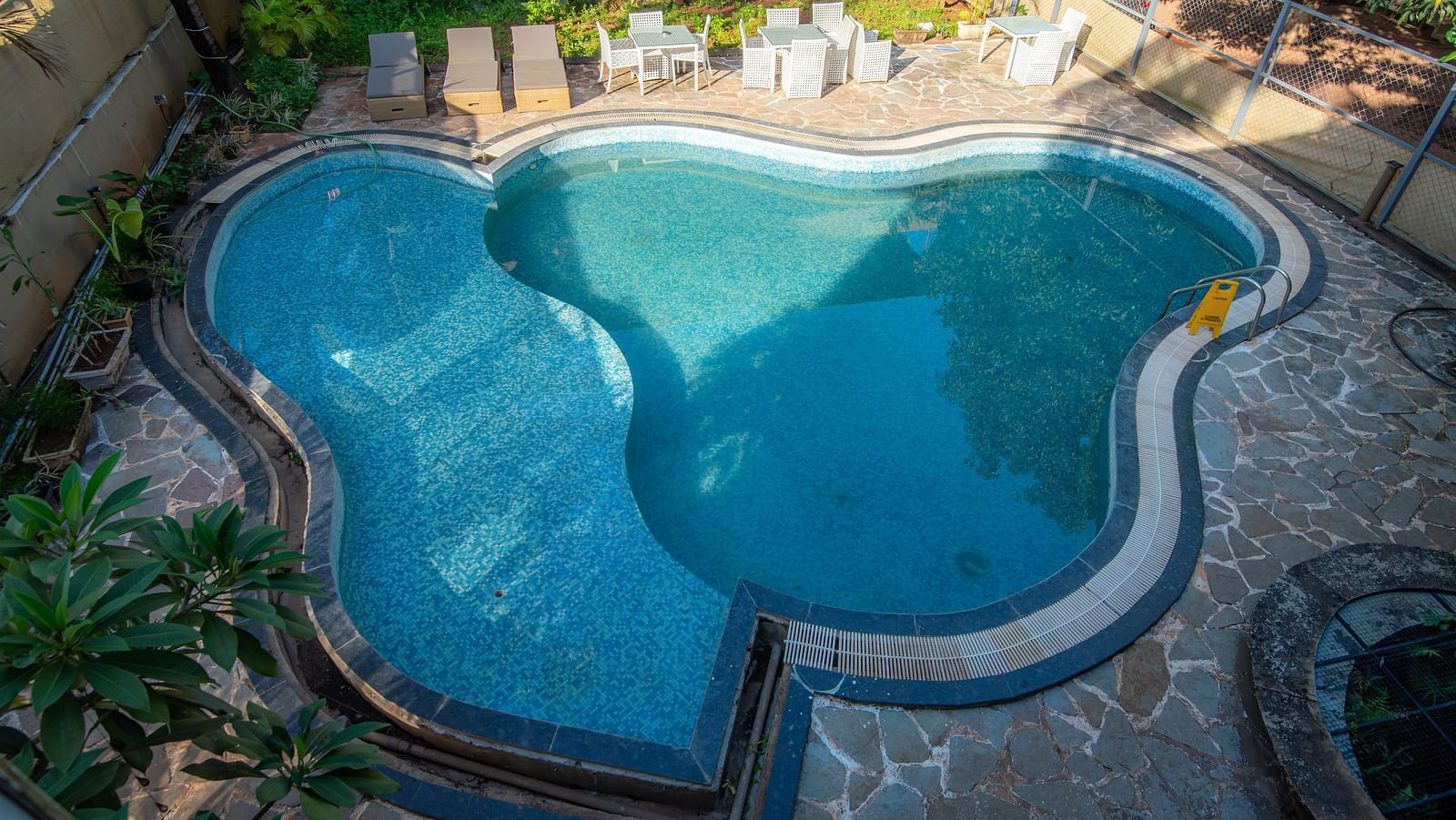 Swimming pool surrounded by plants and seating space at De Soul Santé, Morjim