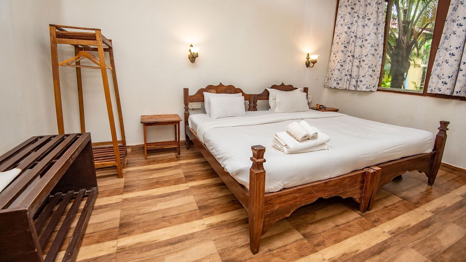 Neatly arranged bedroom with a bed, wooden accents, and a full-length mirror at De Soul Santé, Morjim.