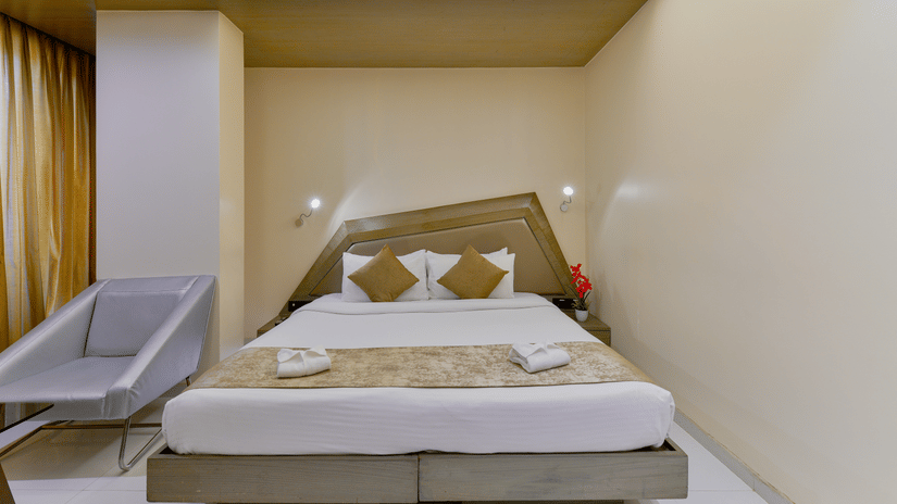 Modern bedroom at Dragonfly Hotels featuring a double bed, beige interiors, and a compact seating area.