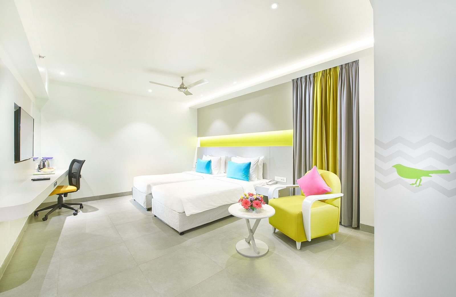 side view of a bedroom featuring a wall-mounted television and a ceiling fan at Zibe Salem by GRT Hotels 