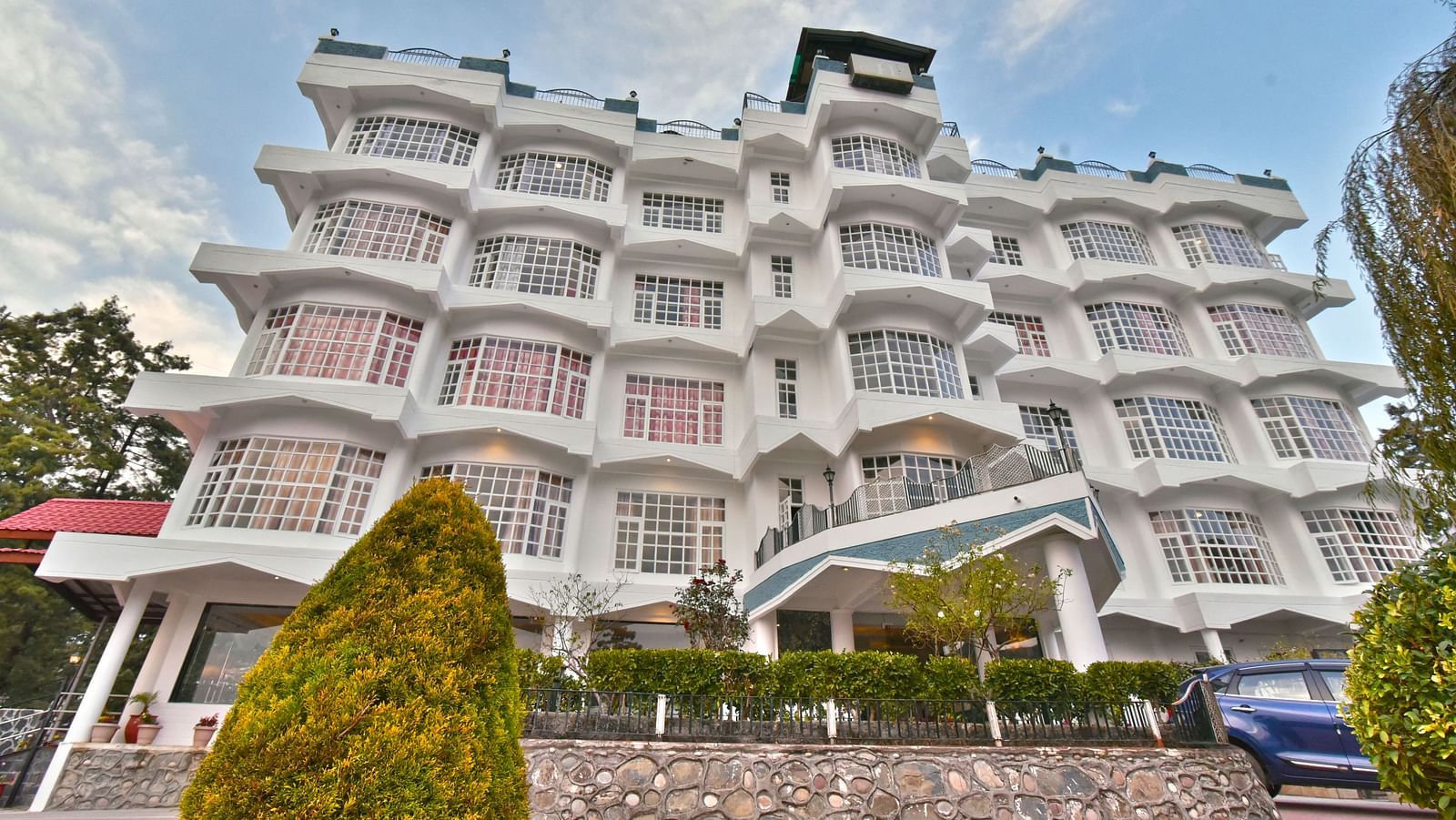 Facade of DLS Hillcrest Resort, Shimla, showcasing the exterior with a lush garden at the front.