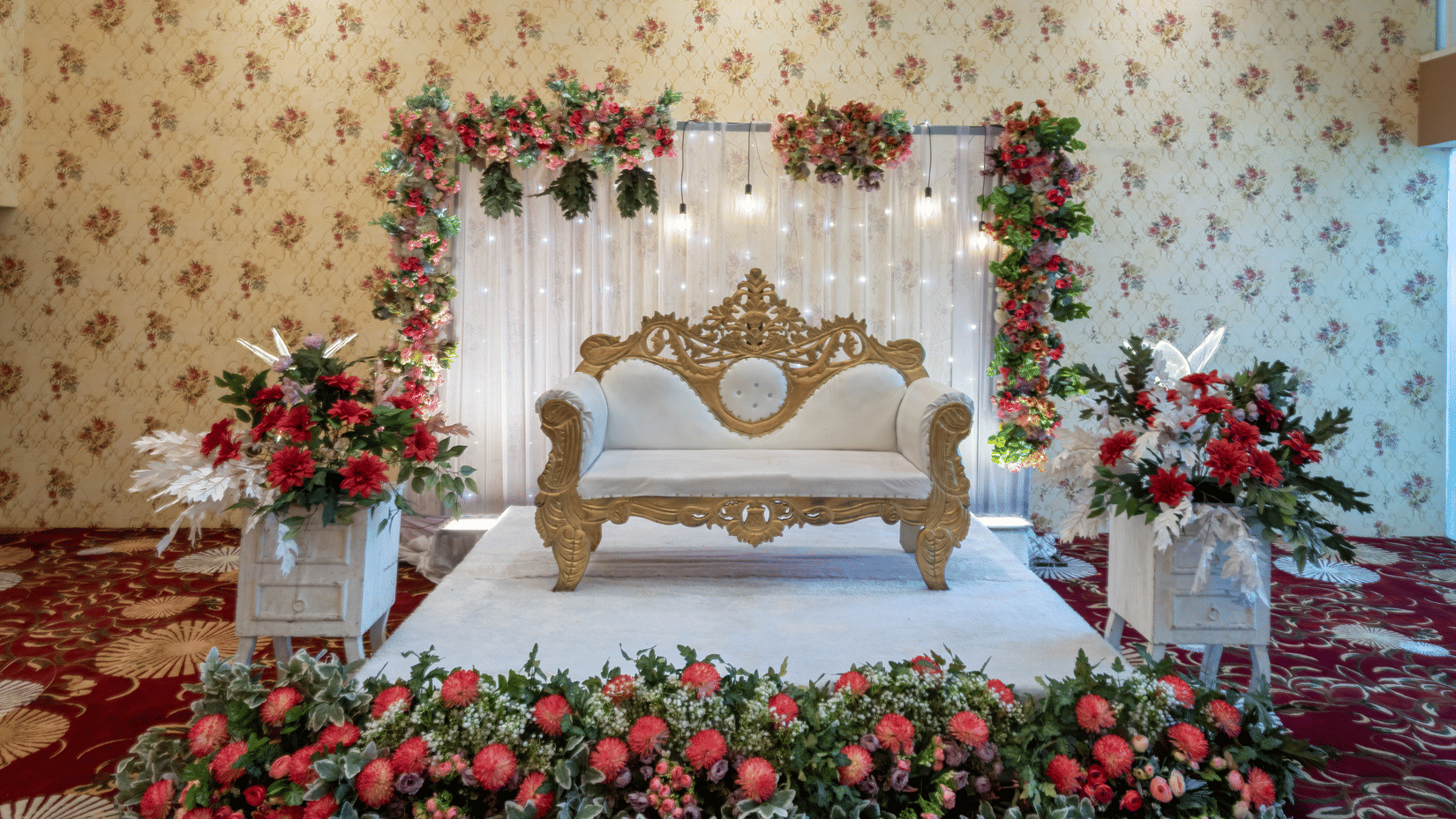Wedding stage decorated with a floral arch and ornate seating at Mango Grove Hotel.