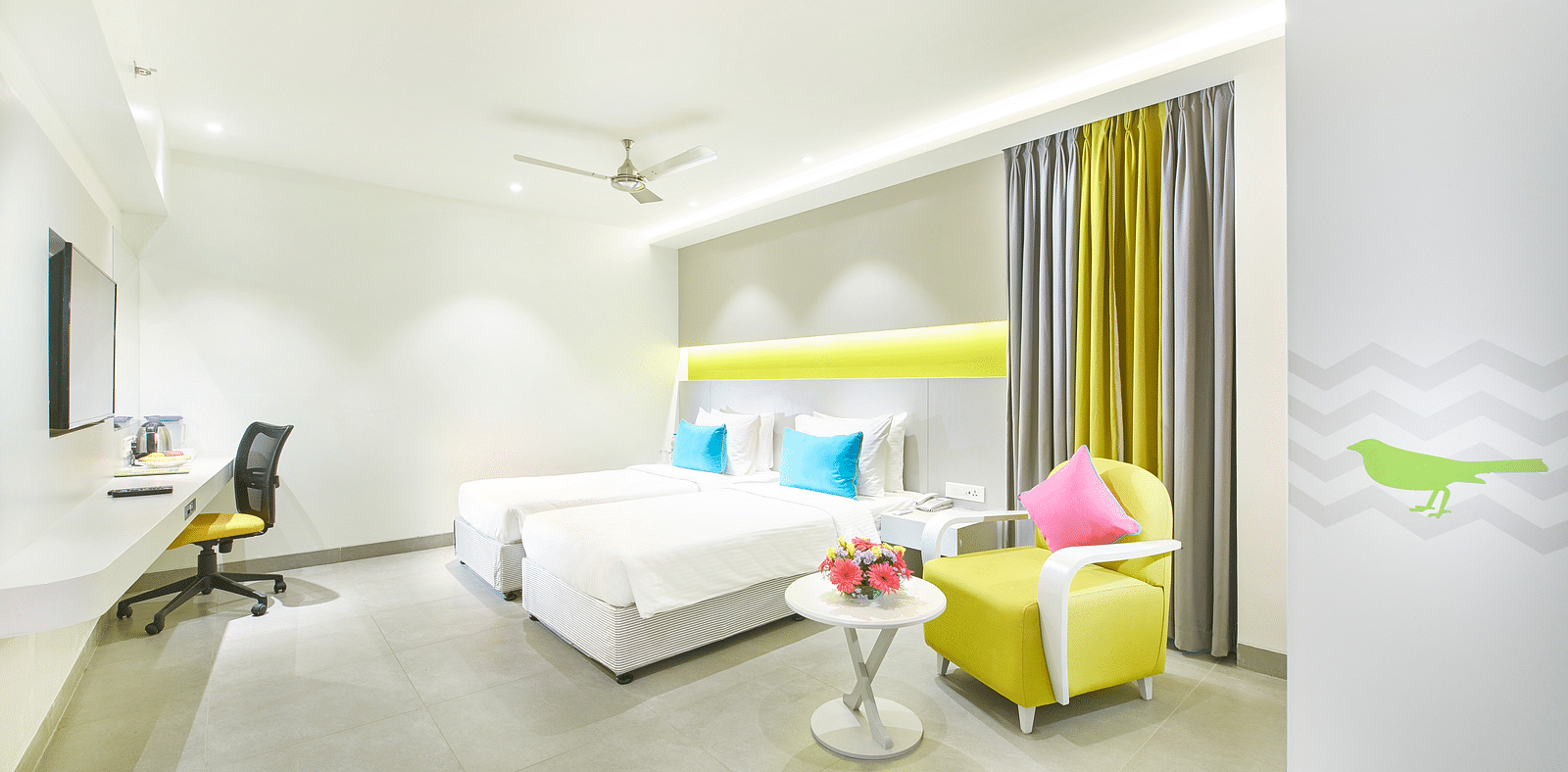 side view of a bedroom featuring a wall-mounted television and a ceiling fan at Zibe Salem by GRT Hotels 