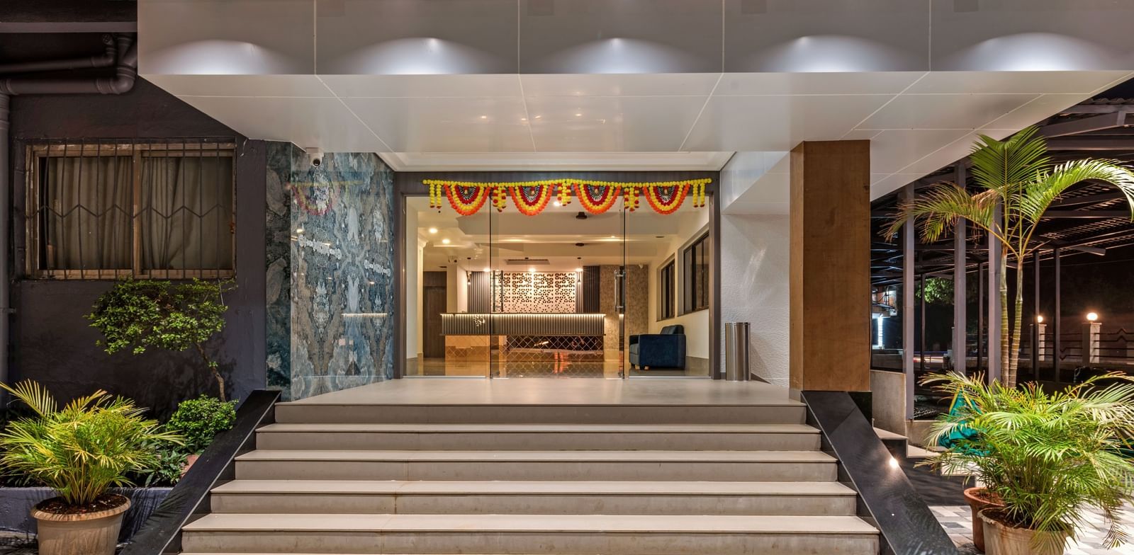 Main entrance of Emerald Retreat, Tungarli with warm lighting, wide steps, and potted plants creating a welcoming ambience.