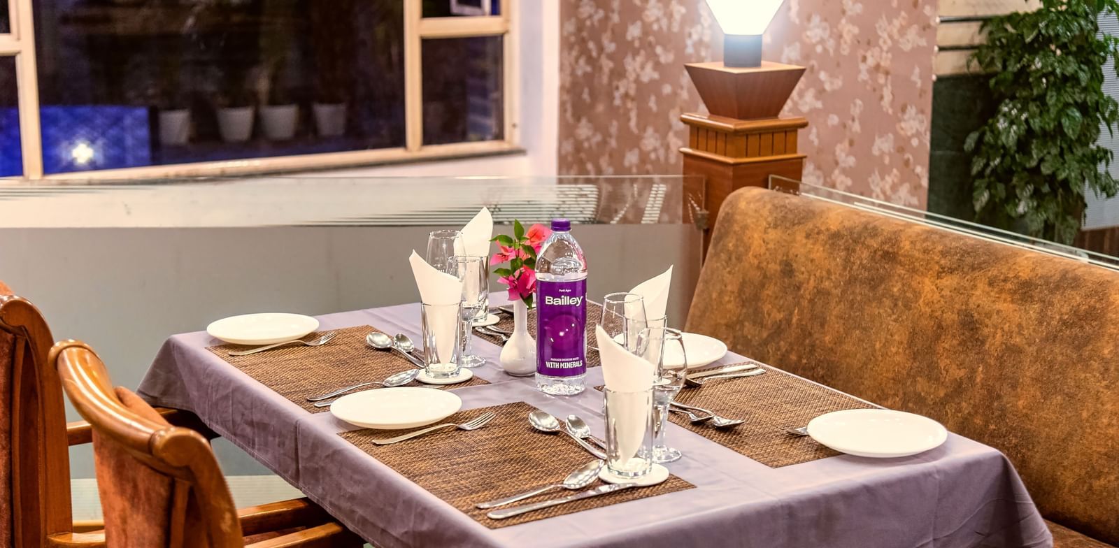 Cosy restaurant seating with a window view, elegantly set tables, and a warm ambience at Mayur Retreat.