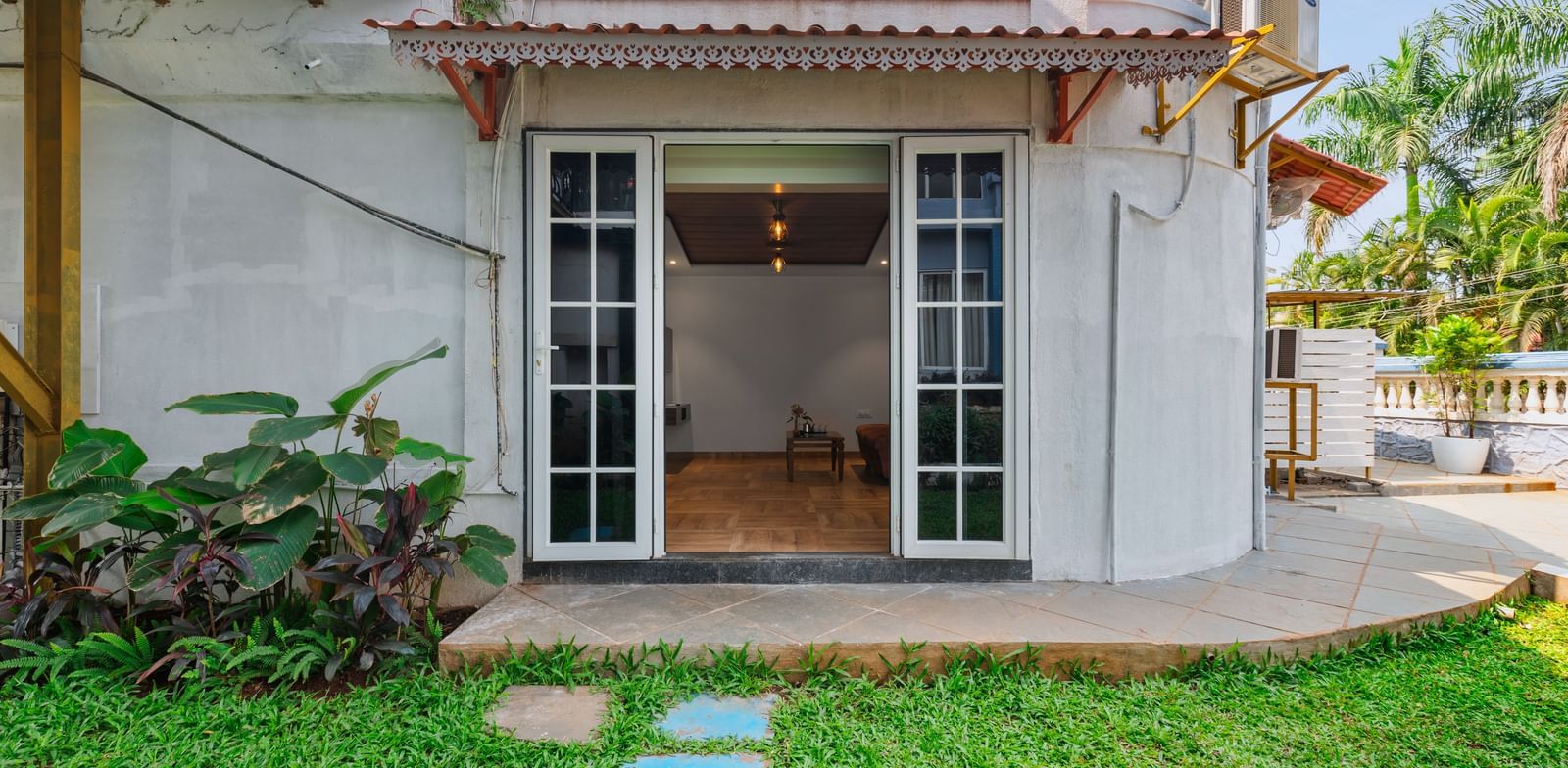 Exterior view of a villa at Mayur Retreat with a private lawn, outdoor seating, and a staircase leading to the upper balcony.