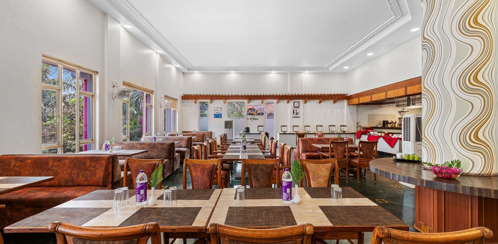 Indoor dining area with wooden furniture and colourful decor, part of The Darbar Restaurant at Mayur Retreat.