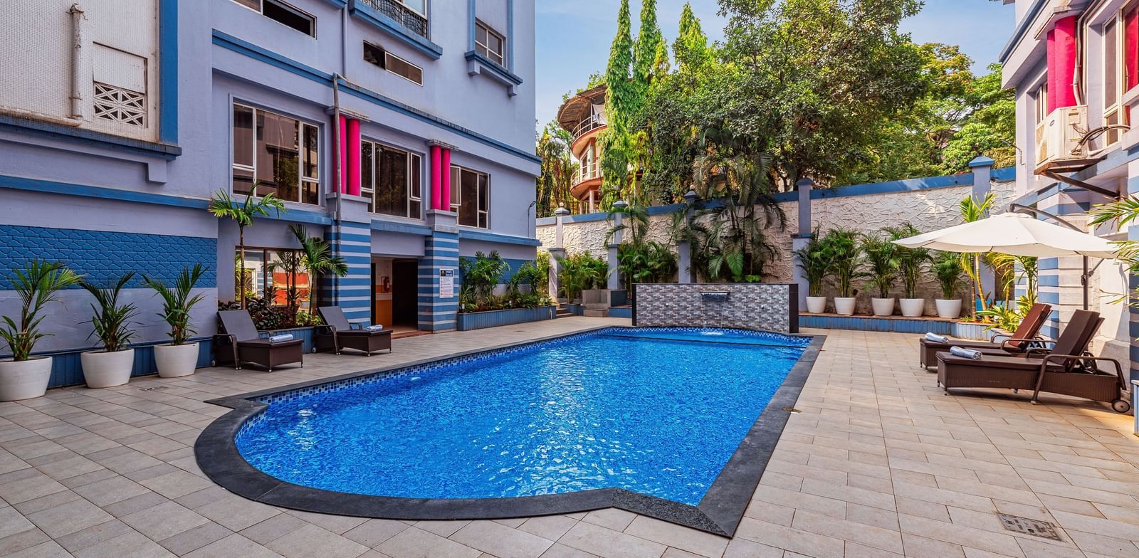 Outdoor swimming pool surrounded by the resort’s vibrant buildings, with poolside seating and lush greenery creating a refreshing leisure space.