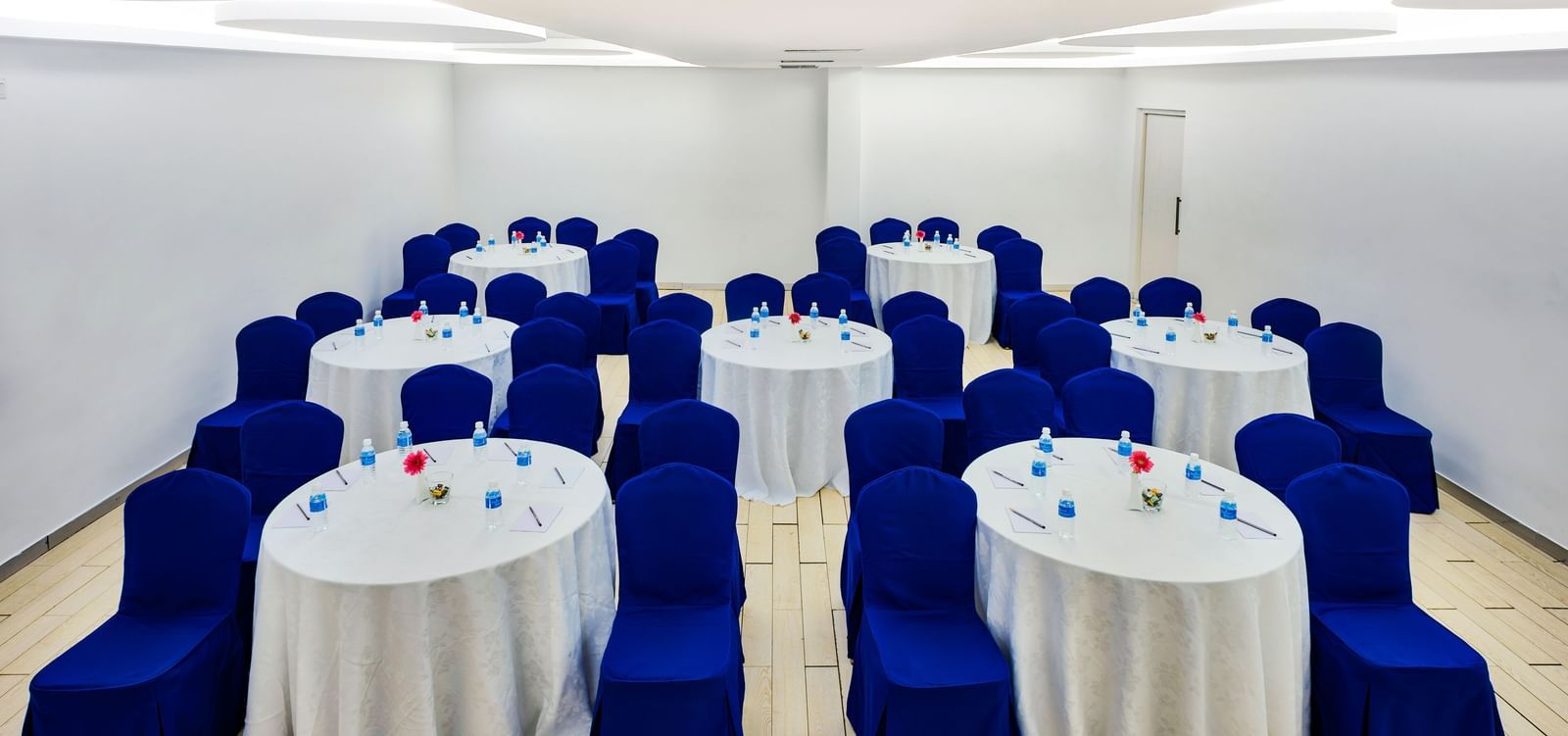 Rows of round banquet tables with white covers and blue chair sashes at Grande Bay Resort & Spa.
