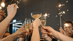 A close up shot of a group of people toasting  glasses and holding firecrackers