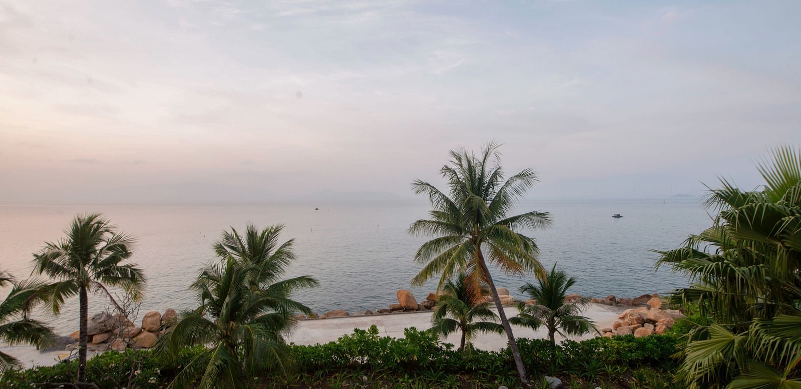A view of palm trees near a sea seen during a sunset through our balcony - Alibu Resort Nha Trang