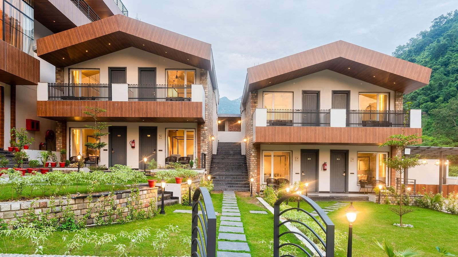 Facade of DLS Divine River Resort and Spa surrounded by lush green gardens and lamp posts.