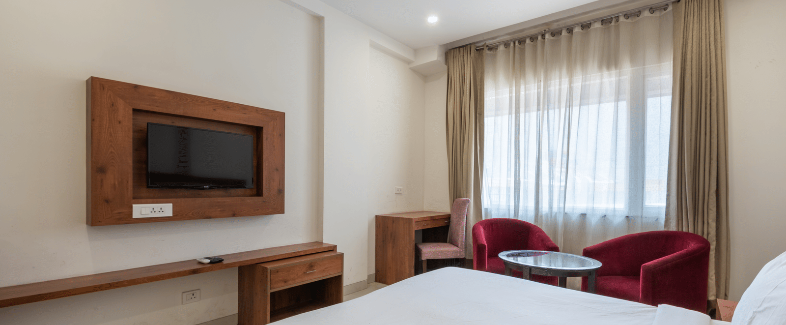 Club balcony room featuring a comfortable bed, wall-mounted TV, and a balcony partially covered by sheer curtains at DLS The Classio