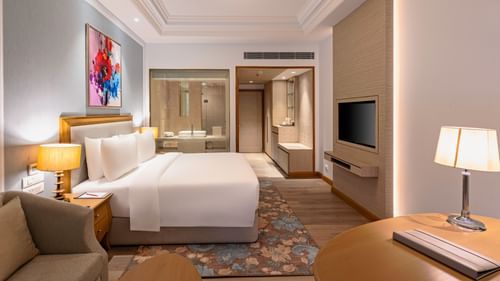 a double bed, side table with a lamp on it, a work desk with a lamp, and a television inside one of the rooms at Park Plaza, Jalandhar