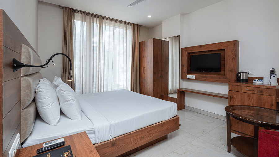 Side view of a Deluxe Room featuring a TV mounted on the wall and a ceiling fan overhead, at DLS The Classio