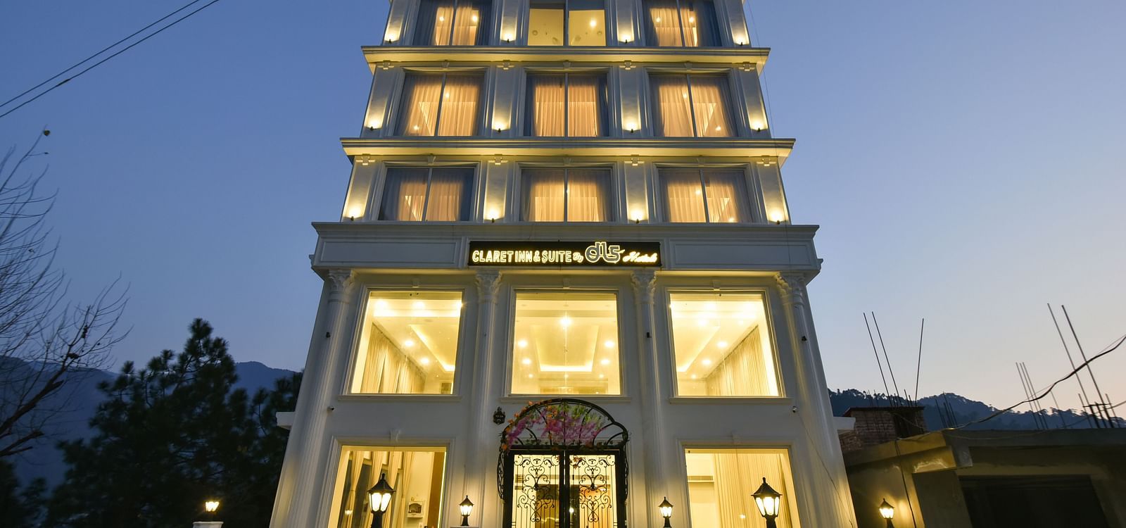 A striking image of a contemporary hotel building with a unique, multi-level design, illuminated at night against the backdrop of mountains.
