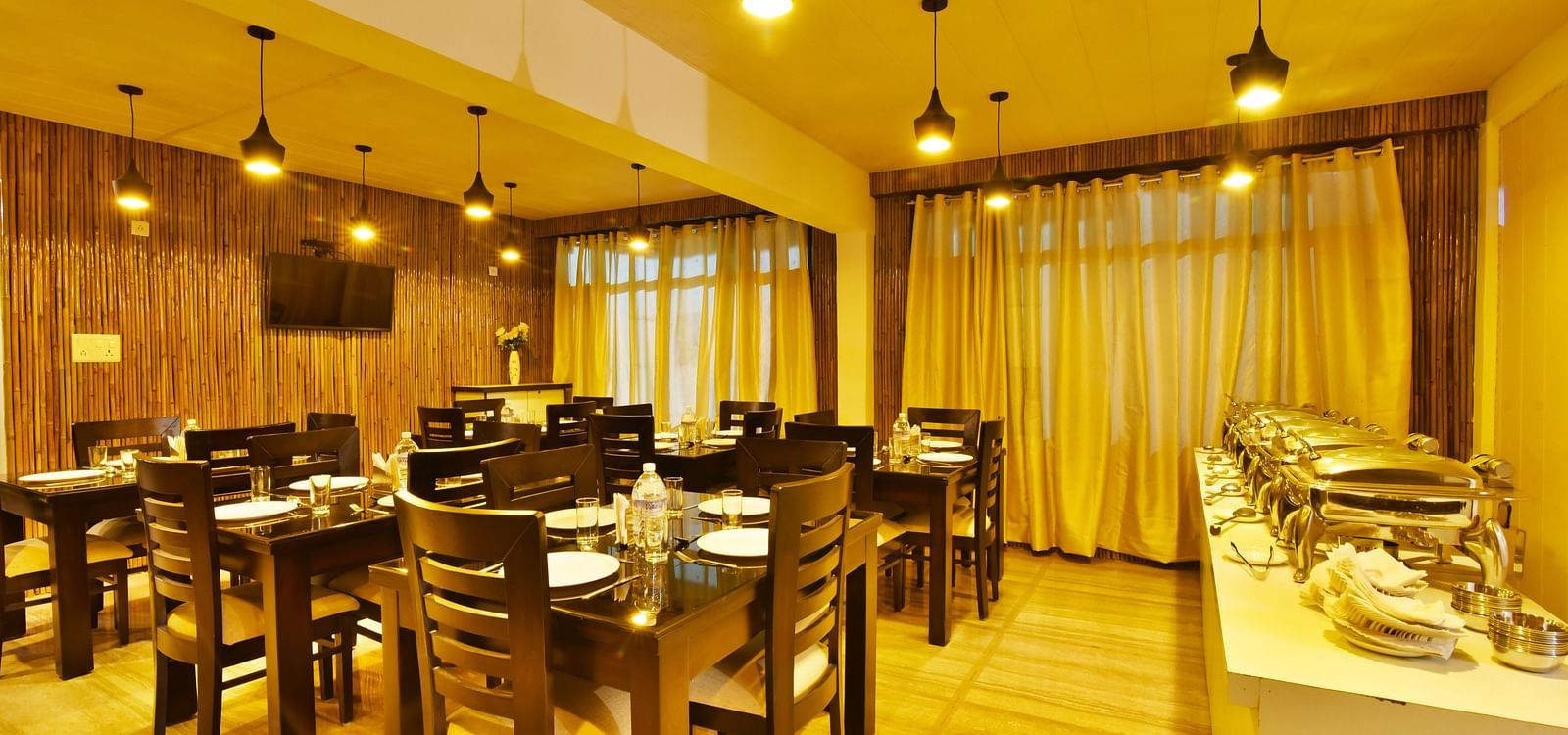 The bright and airy dining room at DLS Kapoor Resorts Manali offers a welcoming space for guests to enjoy their meals.