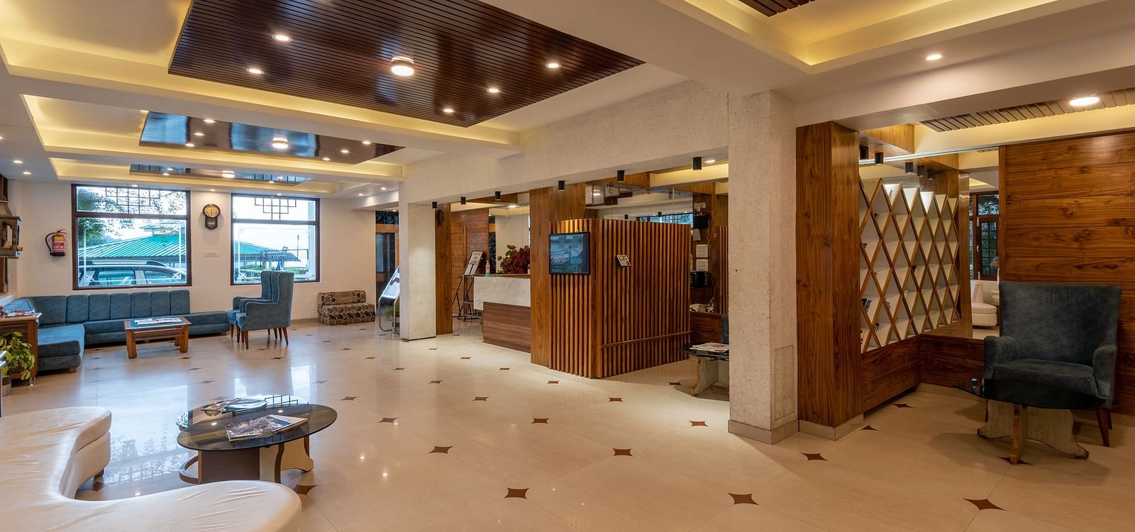 A spacious hotel lobby with a reception desk, comfortable seating areas, and decorative wood panelling - DLS Meghavan Resort