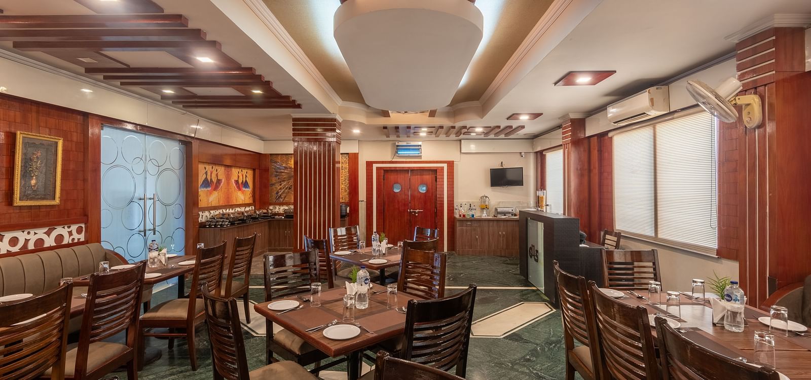Dining area with a designed ceiling and wooden tables and chairs at DLS Park Grace, Haridwar.
