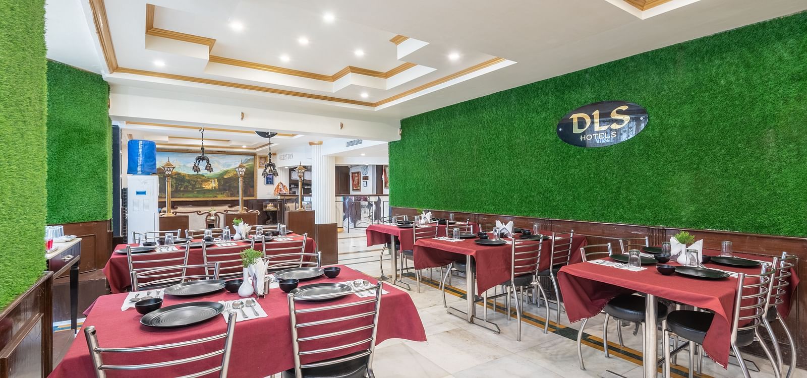 Image of dining area with red tablecloths, metal chairs, and a green wall | DLS The Pearl