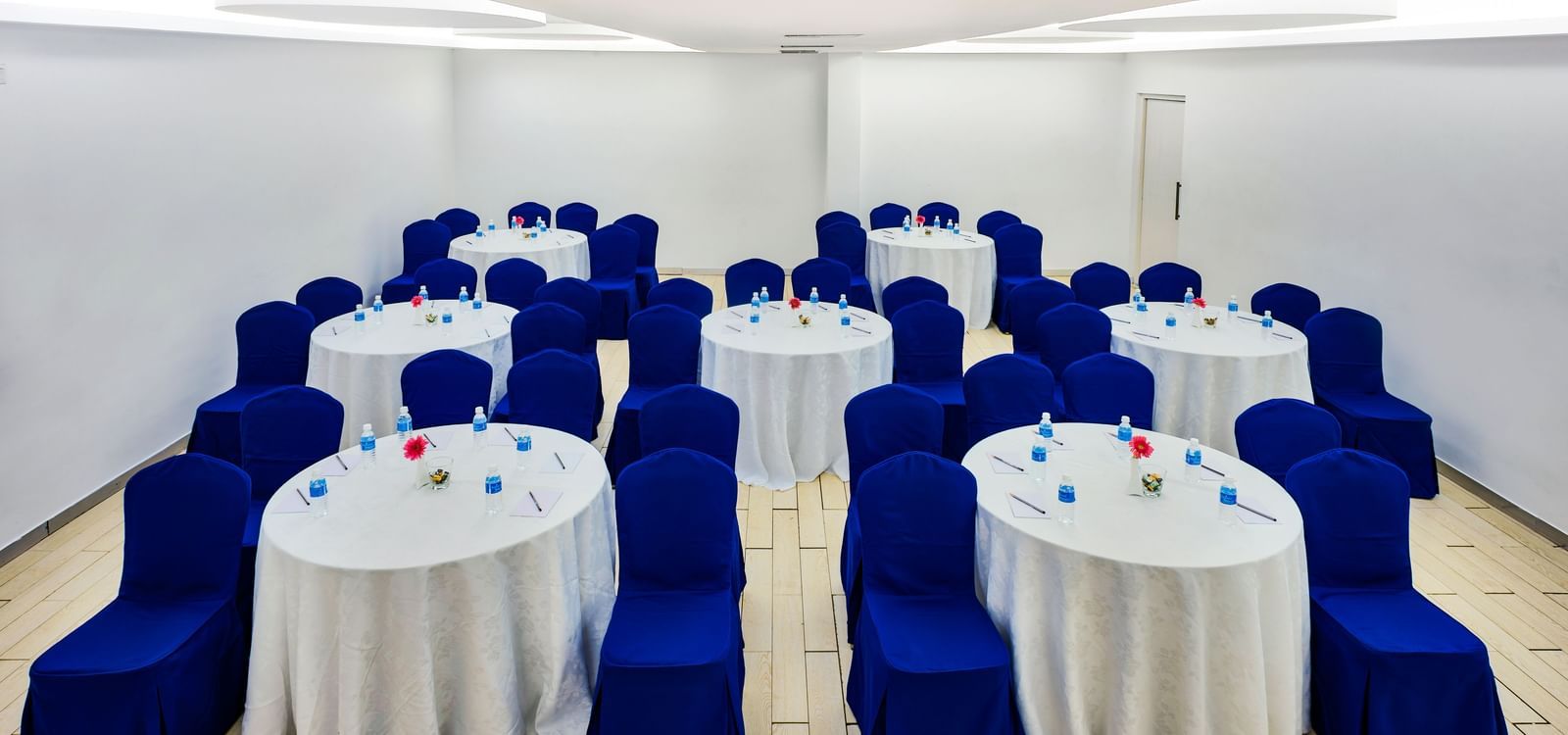 Rows of round banquet tables with white covers and blue chair sashes at Grande Bay Resort & Spa.