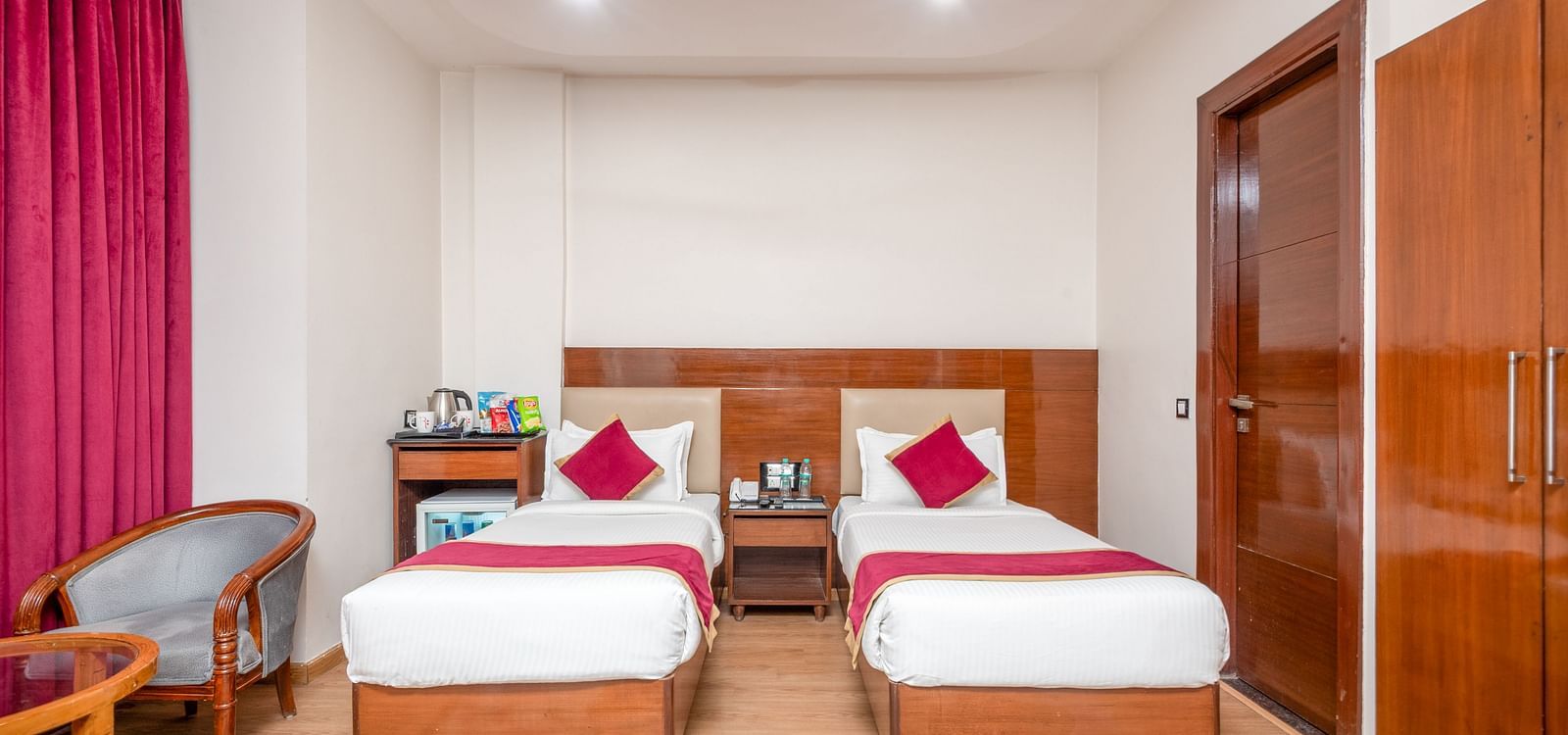 Twin bed room with pink curtains at Regenta Inn DLS, Rishikesh.