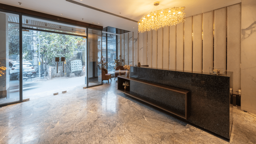 A reception area with a desk, chandelier, glass entrance, and open space inside at DLS Hotels Amritsar.