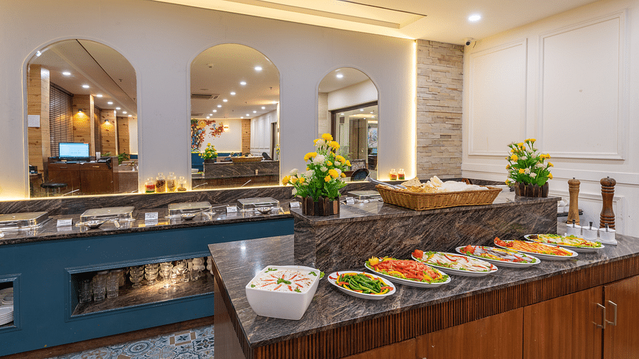 A restaurant with fresh salads and a buffet setup, illuminated by warm yellow lights in the background at DLS The Classio