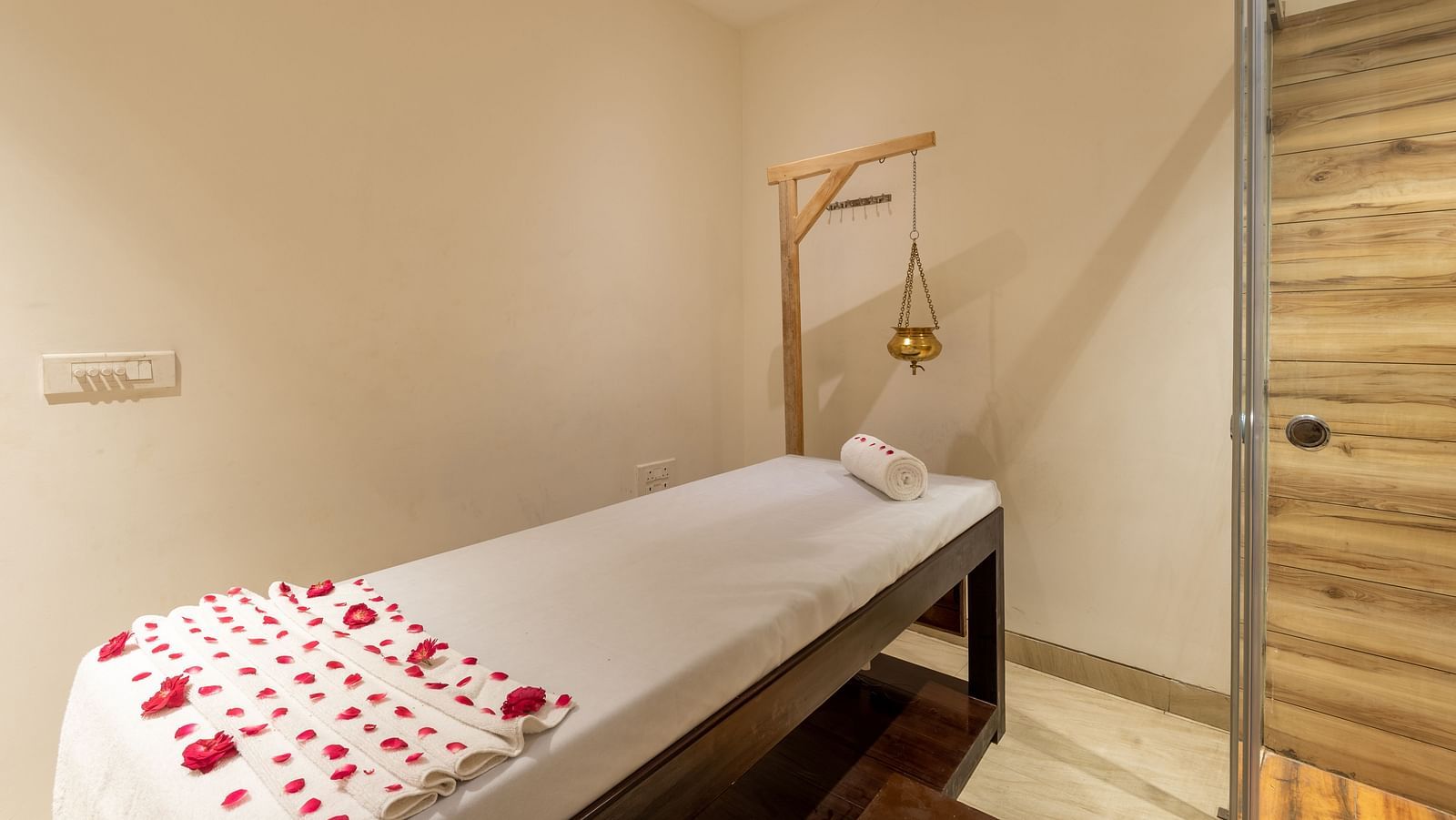 image of spa with a bed decorated with rose petals and a Shirodhara vessel at DLS The Classio