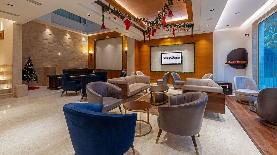 A hotel lobby with chairs, carpet, table, Christmas-themed decorations, and a wall-mounted TV at Hotel Saket 27, New Delhi