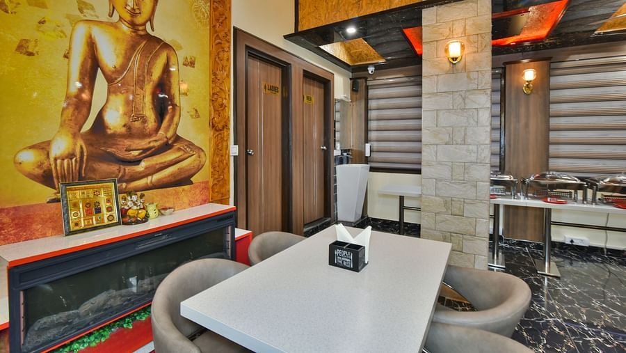 Restaurant at DLS Dalhousie Valley Resort with chairs, tables and a painting.