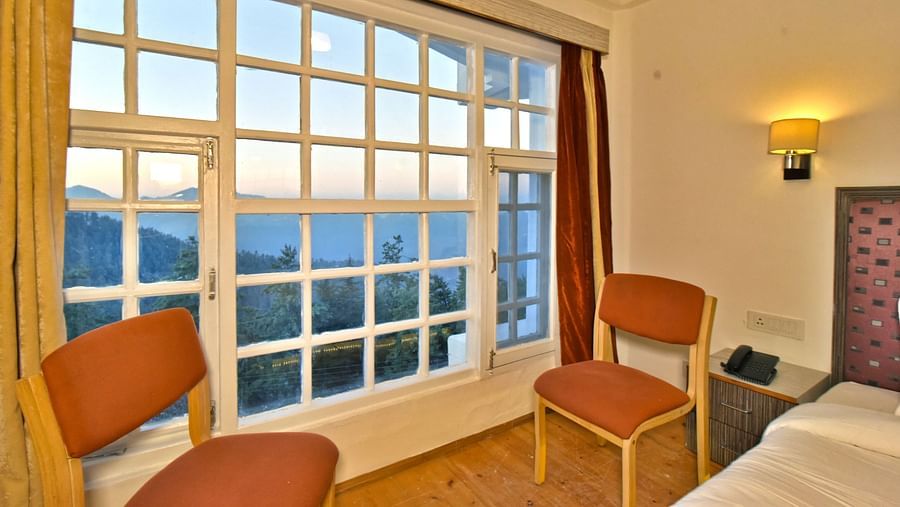 Seating area in the bedroom next to the window at DLS Hillcrest Resort, Shimla.
