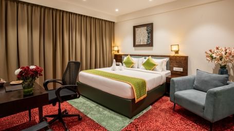 Elegant room with king size bed, seating area, and modern decor at Hotel Royal Regency Chennai