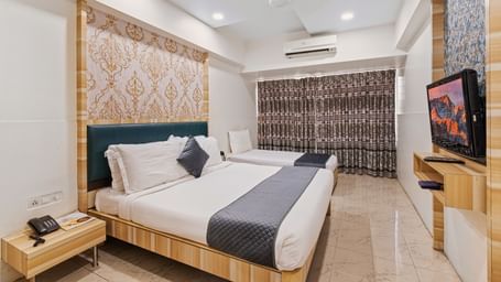 Modern hotel room with a king size bed and a singe bed at Mayur Retreat, contemporary lighting, and a flat-screen TV for a comfortable stay.