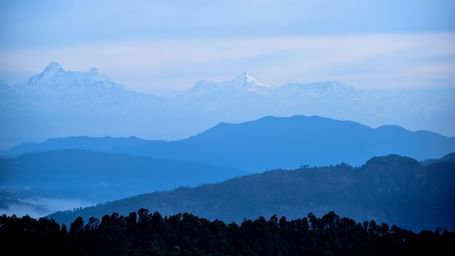 Misty mountain ranges with rolling hills layered beneath a clear sky