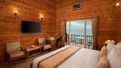 a hotel room with a double bed, a seating area, a wall-mounted television and a balcony with stunning vistas - Highland Sarovar Portico, Sindhudurg