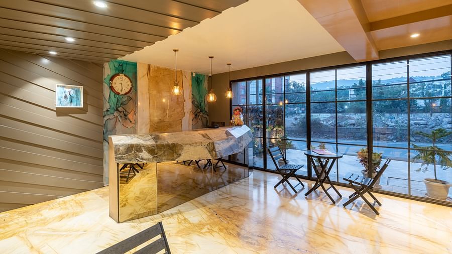 A shot of the reception area taken from an angle showcasing the waiting area and the wide glass door - DLS Hotel Arihant, Haridwar