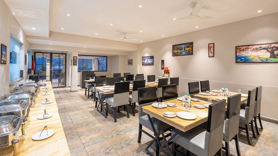 The indoor restaurant set up with chairs and tables along with a buffet table on the left at DLS Hotel Arihant, Haridwar