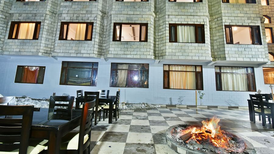 The exterior of DLS Kapoor Resorts Manali by DLS Hotels at night, illuminated with warm lights, showcases its stone facade