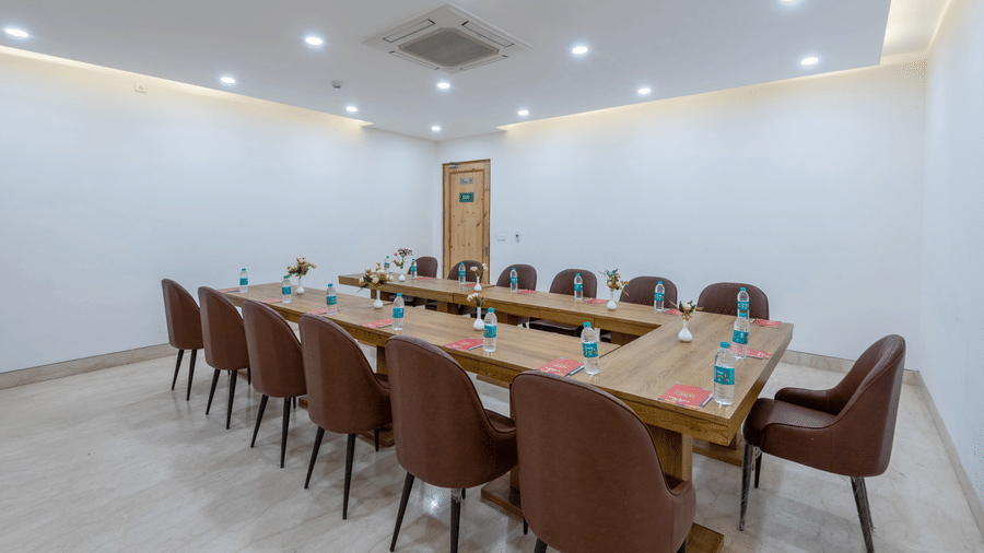 Side view of a conference room with multiple chairs, an air conditioner, and water bottles placed on the table at DLS The Classio