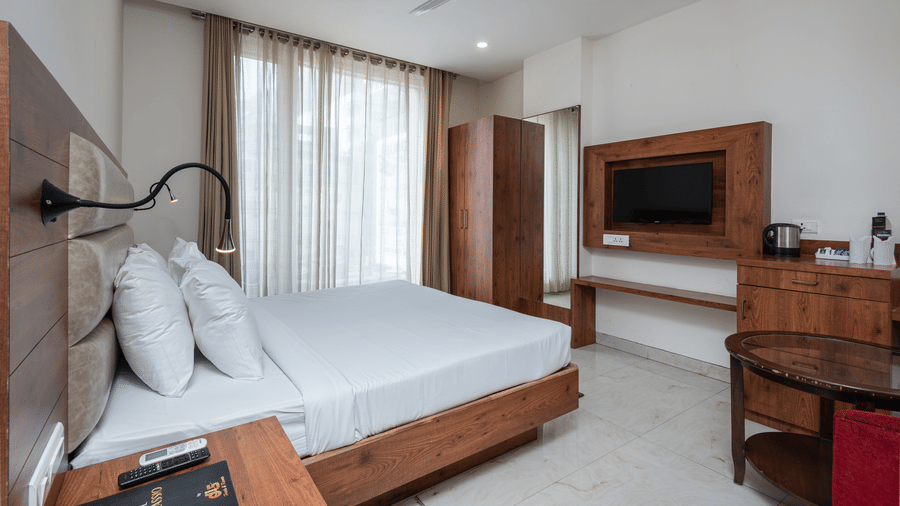Side view of a Deluxe Room featuring a TV mounted on the wall and a ceiling fan overhead, at DLS The Classio