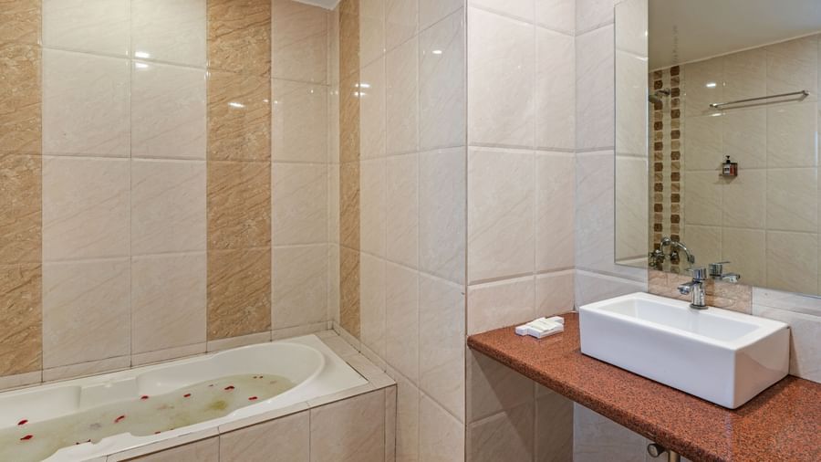 Modern tiled bathroom at Emerald Retreat, Tungarli with a built-in bathtub and sleek vanity unit.
