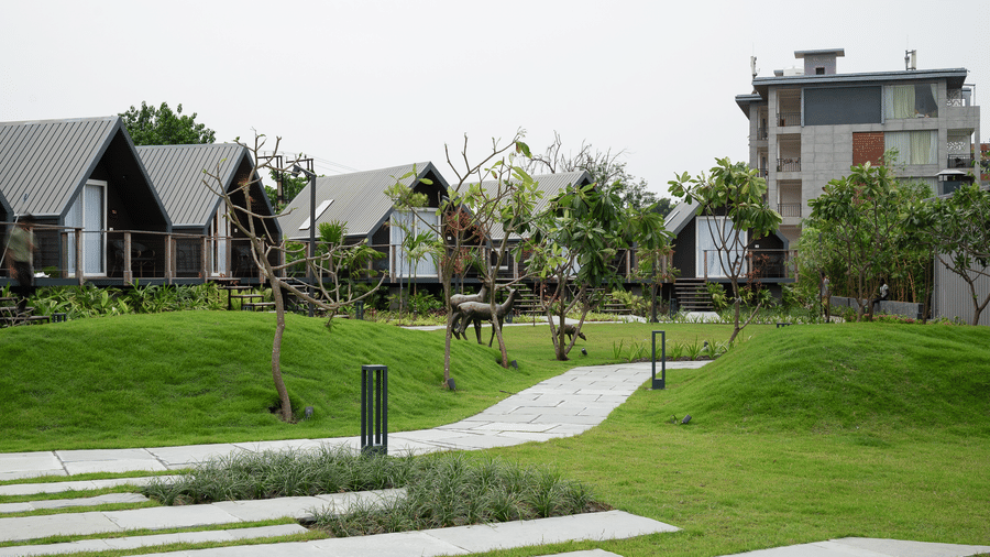 Exterior view of the rooms across a landscaped lawn with a curved path at Hotel Sonar Bangla, Taki.