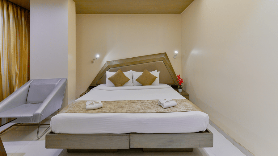 Modern bedroom at Dragonfly Hotels featuring a double bed, beige interiors, and a compact seating area.