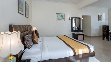 Image of a king size bed in an expansive suite with a side lamp | DLS The Pearl