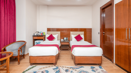 Twin bed room with pink curtains at DLS Hotels On The Ganges.