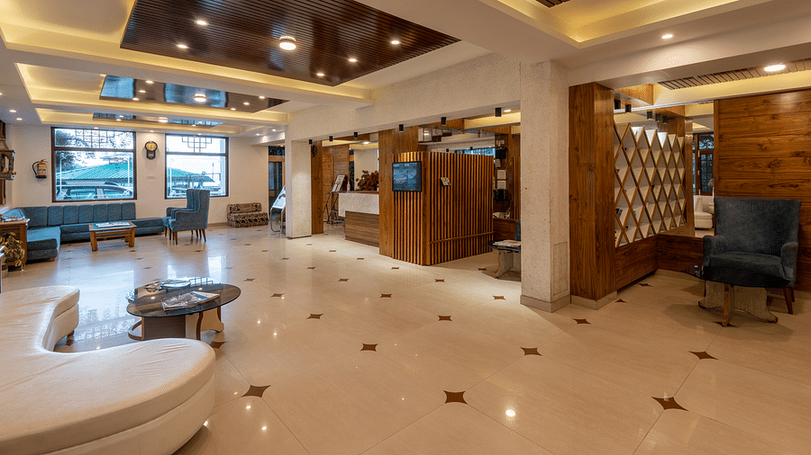 A spacious hotel lobby with a reception desk, comfortable seating areas, and decorative wood panelling - DLS Meghavan Resort