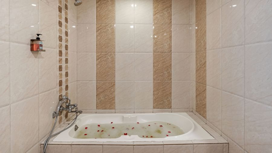 Bathroom featuring a clean modern design with beige tiles and a built-in bathtub with overhead shower at Emerald Retreat, Tungarli.