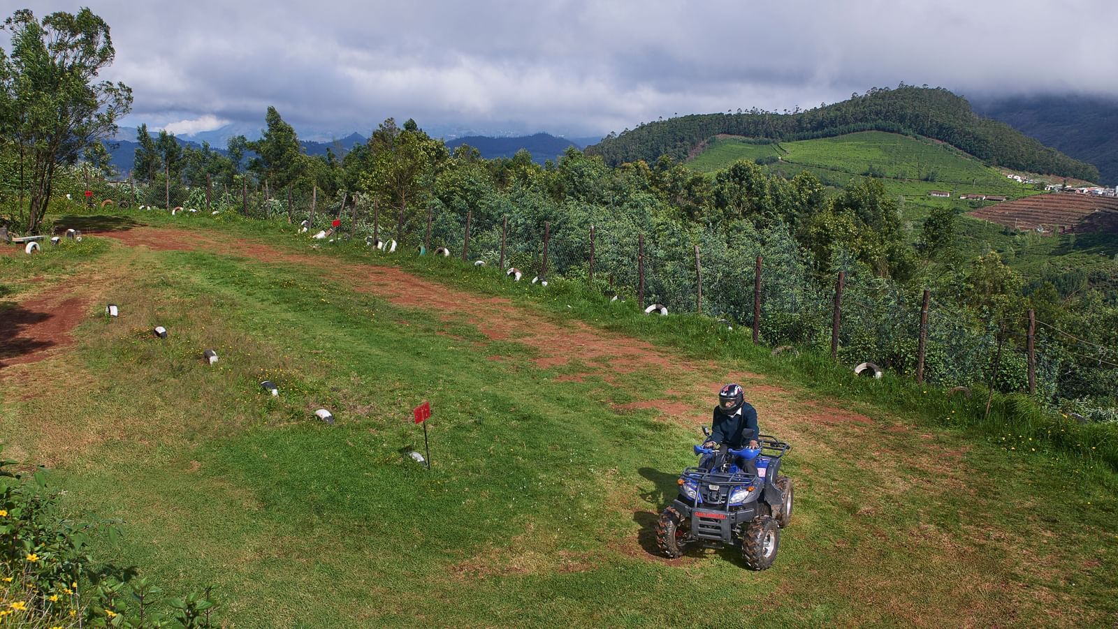 A person riding an ATV on a trail on a cloudy day at Accord Highland Ooty